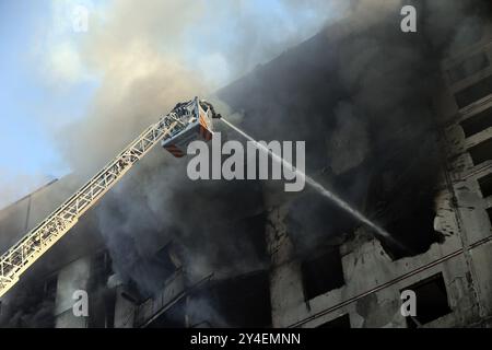 KHARKIV, UKRAINE - 15 SEPTEMBRE 2024 - des secouristes sur une plate-forme élévatrice éteignent un incendie dans le bâtiment résidentiel touché par une bombe aérienne guidée russe, Kharkiv, dans le nord-est de l'Ukraine Banque D'Images