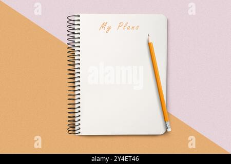 Au-dessus du plafond gros plan manuel, accompagné d'un crayon sur un fond géométrique coloré, symbolisant la planification, la créativité et l'intention Banque D'Images