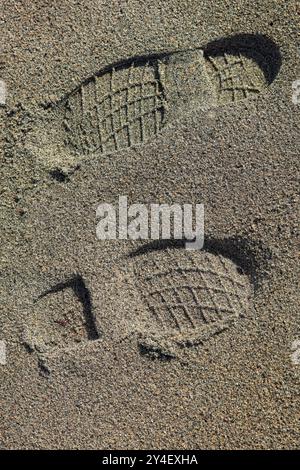 Gros plan des empreintes de bottes dans le sable doux sur la plage. Banque D'Images