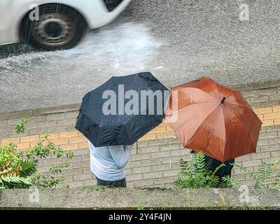 Conversation secrète, sous les parapluies : deux hommes se réunissant un jour de pluie. Et une partie de la voiture blanche, pneu noir en mouvement flou Banque D'Images