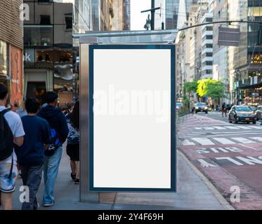 Maquette de panneau d'affichage blanc vide vertical à l'arrêt de bus à New York. En arrière-plan bâtiments et route. Banque D'Images