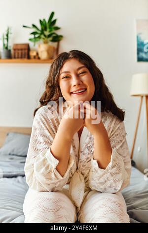 Une jeune femme joyeuse profite de son temps à la maison, rayonnant de confiance dans une tenue confortable. Banque D'Images