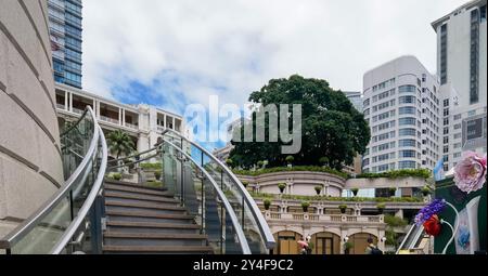 Hong Kong, Chine - 18 septembre 2024 : escalier moderne en verre avec garde-corps en acier menant à un bâtiment traditionnel avec de grandes fenêtres, pla en pot Banque D'Images