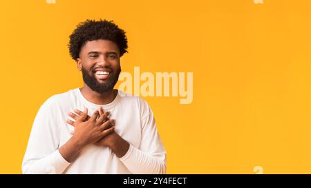 Smiling african man en plaçant les mains à côté de coeur Banque D'Images