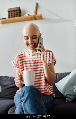 La femme joyeuse sourit et sirote sa boisson tout en discutant au téléphone, rayonnant de positivité. Banque D'Images