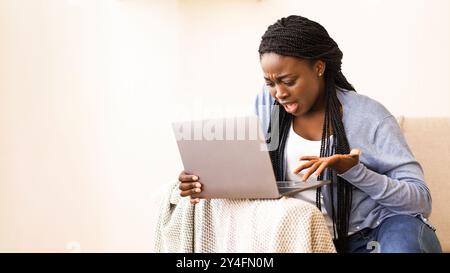 Afro girl frustrés des problèmes avec l'ordinateur portable à la maison Banque D'Images