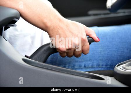 Conducteur féminin à main tirant le frein à main à l'intérieur de la voiture Banque D'Images