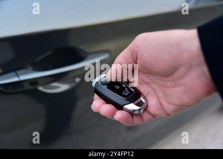 La main féminine appuie sur le système d'alarme de voiture à télécommande Banque D'Images