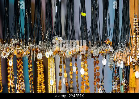 Une variété de colliers fabriqués à la main accrochent à un étalage de marché dynamique. Banque D'Images