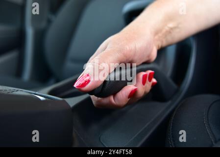 Conducteur féminin à main tirant le frein à main à l'intérieur de la voiture Banque D'Images