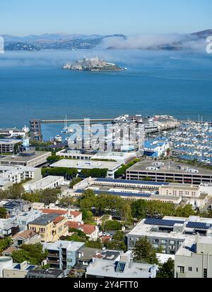 Pier 39 zone marina avec l'île d'Alcatraz sous un ciel brumeux. Banque D'Images