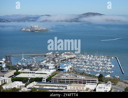 Pier 39 zone marina avec l'île d'Alcatraz sous un ciel bleu brumeux. Banque D'Images