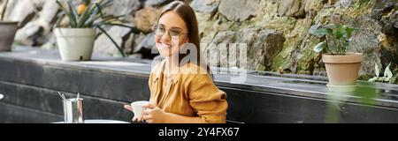 Une jeune femme savoure son café dans un charmant café, rayonnant de confiance et de positivité. Banque D'Images