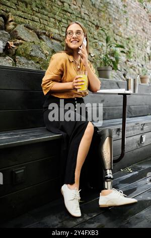 Dans un café confortable, une jeune femme sirote sa boisson confortablement assise, rayonnant de joie et de confiance. Banque D'Images