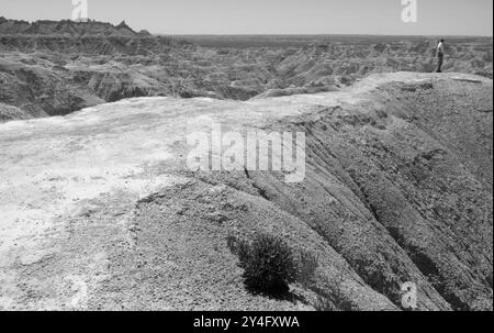 Un homme caucasien debout sur une colline, profitant du paysage à couper le souffle du parc national des Badlands à l'intérieur, Dakota du Sud, États-Unis. Banque D'Images