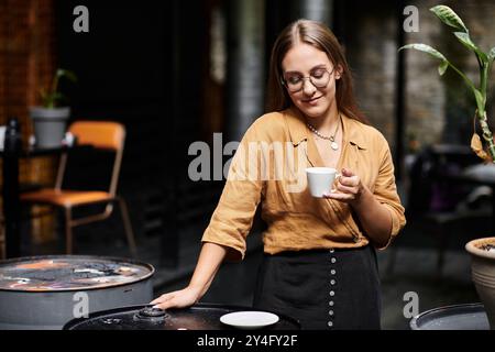 Dans un charmant café, une jeune femme savoure son café tout en se prélassant dans une ambiance vibrante. Banque D'Images