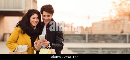 Jeune couple profitant du shopping ensemble dans la ville pendant le coucher du soleil Banque D'Images