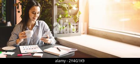 Young woman looking at smartphone et de boire du café Banque D'Images