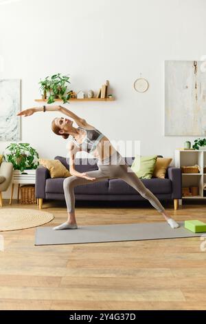 Dans un salon confortable, une jeune femme anorexique embrasse son parcours de bien-être à travers le yoga, découvrant force et équilibre. Banque D'Images
