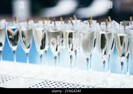 Verres avec du vin mousseux froid debout sur un comptoir dans une rangée, piscine à l'arrière, bar de fête. Banque D'Images