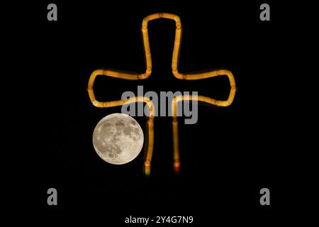 Aqosh, Irak. 17 septembre 2024. La pleine lune se lève derrière une croix placée au sommet d'un bâtiment dans la ville irakienne d'Alqosh, à 50 km au nord de Mossoul. (Photo de Ismael Adnan/SOPA images/SIPA USA) crédit : SIPA USA/Alamy Live News Banque D'Images