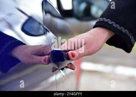 Une femme ouvre la porte de la voiture Banque D'Images