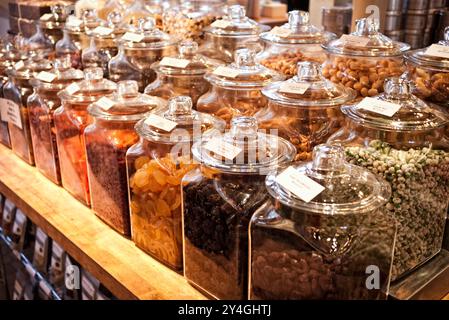 Fruits séchés et noix en pots affichage du marché alimentaire // WASHINGTON DC — les fruits séchés et les noix sont exposés pour la vente dans des bocaux en verre disposés en rangées soignées sur un marché alimentaire haut de gamme. Les contenants transparents présentent une variété de fruits secs de première qualité, y compris des abricots, des figues et des dattes, ainsi que des noix assorties telles que des amandes, des noix et des pistaches. Ce type d'affichage d'aliments de spécialité est courant dans les marchés gastronomiques et les épiceries fines qui mettent l'accent sur le merchandising visuel et la qualité des produits. La présentation organisée permet aux clients de visualiser facilement la sélection tout en maintenant la fraîcheur et l'hygiène Banque D'Images