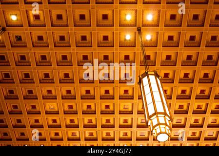 Plafond à caissons de la 30th Street Station Philadelphie Pennsylvanie // PHILADELPHIE, Pennsylvanie — le motif géométrique du plafond à caissons de la 30th Street Station de Philadelphie comporte des luminaires suspendus à des panneaux encastrés. Le plafond d'influence néoclassique et art déco fait partie du hall principal de cette gare ferroviaire historique, qui sert de plaque tournante de transport pour les services ferroviaires Amtrak et SEPTA. Conçue par le cabinet d'architectes Graham Anderson Probst & White, la station a été achevée en 1933 pendant la Grande dépression et est inscrite au National Reg Banque D'Images