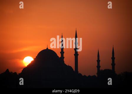 Silhouette de la mosquée Süleymaniye au coucher du soleil Istanbul Turquie // ISTANBUL, Turquie — la mosquée Süleymaniye est dessinée contre un coucher de soleil doré. Construite au XVIe siècle sous le règne du sultan Suleiman le magnifique, la mosquée a été conçue par le maître architecte ottoman Mimar Sinan. Quatre minarets et le massif dôme central définissent la silhouette emblématique de ce complexe de mosquée impériale. Banque D'Images