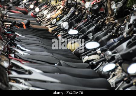 HANOI, Vietnam — Une longue rangée de motos et de scooters est alignée sur le côté d'une rue dans le vieux quartier de Hanoi. La scène reflète la dépendance de la ville aux deux-roues pour le transport, un spectacle commun dans cette partie animée du Vietnam. Banque D'Images