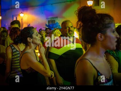 Un mari et une femme dans une foule de gens italiens en train de se réjouir d'un concert nocturne gratuit en plein air sur la place de Depressa, un village des Pouilles, en Italie. Banque D'Images