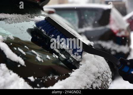 Enlever la neige de la vitre de la voiture avec une brosse Banque D'Images