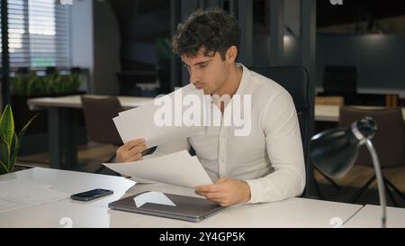 Caucasien occupé homme d'affaires concentré travail dans le bureau Guy homme d'affaires homme de travail paperasse vérifier les documents statistiques financières les papiers de données lus Banque D'Images