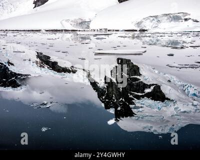 Les eaux miroitantes reflec le paysage accidenté de l'île de Cuverville sur le côté ouest de la péninsule antarctique. Banque D'Images