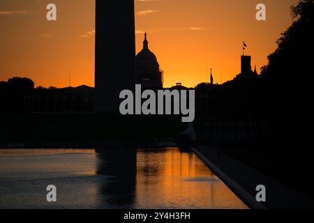 WASHINGTON DC, États-Unis — le Washington Monument, le dôme du Capitole des États-Unis et la piscine réfléchissante vus depuis le Lincoln Memorial au lever du soleil pendant l'équinoxe de printemps et d'automne. Le soleil se lève parfaitement aligné avec le National Mall, projetant une lueur chaude sur les monuments emblématiques. Banque D'Images