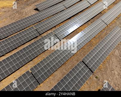 Un drone capture une vue aérienne de rangées de panneaux solaires installés dans un champ rural, présentant des solutions énergétiques durables pour un avenir plus vert Banque D'Images