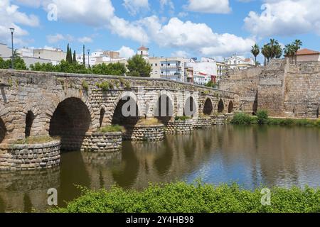 Pont de pierre historique sur une rivière avec mur de la ville en arrière-plan sous un ciel bleu et atmosphère d'été, pont romain, Puente Romano, pont en arc w Banque D'Images