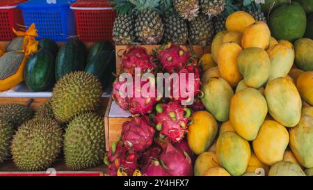 Mangue, pitahaya, durian et ananas sur le comptoir dans un magasin en Thaïlande à un marché de rue. Assortiment de fruits tropicaux vietnamiens exotiques mûrs sucrés Banque D'Images