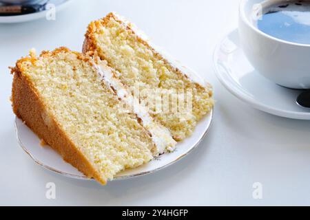 Une seule plaque grande portion d'un gâteau au citron fait maison servi à une table. Le gâteau a une garniture de crème au beurre au citron et un glaçage à la crème au beurre Banque D'Images