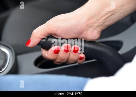 Conducteur féminin à main tirant le frein à main à l'intérieur de la voiture Banque D'Images