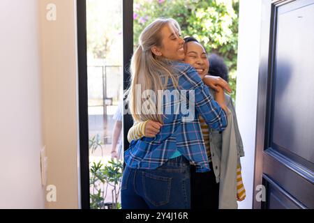 Amis serrés et souriants, se saluant chaleureusement à la porte d'entrée Banque D'Images