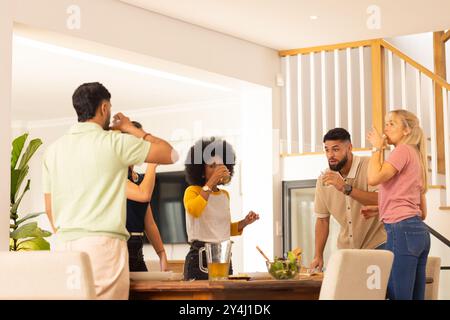 Amis buvant du jus ensemble dans la cuisine moderne, appréciant la réunion décontractée Banque D'Images