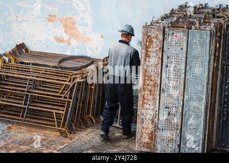 Ouvrier brésilien du bâtiment organisant des pièces d'échafaudage sur un chantier de construction à Belo Horizonte, Brésil. Banque D'Images