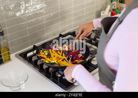 Cuisson de légumes colorés dans un wok, personne préparant un repas sain à la maison Banque D'Images