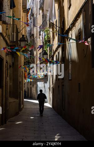 Un homme marche dans une rue étroite du quartier gothique de Bari à Barcelone, en Espagne. Banque D'Images