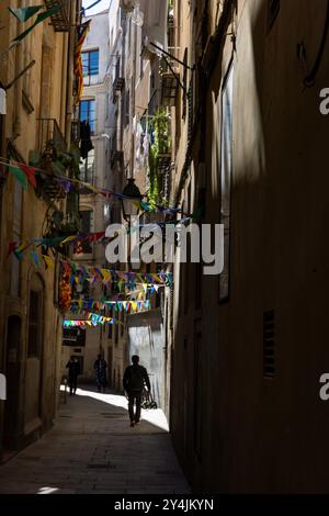 Un homme marche dans une rue étroite du quartier gothique de Bari à Barcelone, en Espagne. Banque D'Images