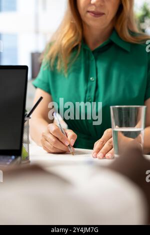 Personne écrivant avec un stylo sur des papiers contractuels après des qualifications alignées sur les attentes de l'entreprise. Gros plan du candidat remplissant des fichiers de formulaire de demande après avoir rendu le recruteur satisfait avec CV Banque D'Images