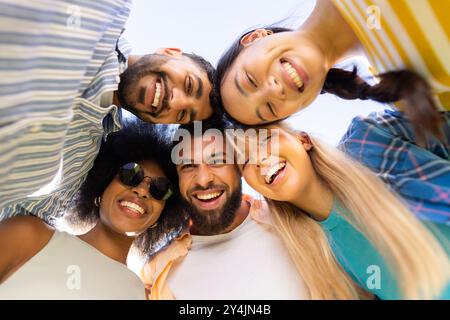 Groupe de jeunes amis divers souriant et regardant vers le bas à la caméra, profitant du temps ensemble Banque D'Images