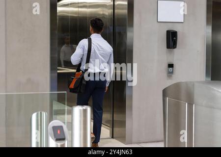 Entrant ascenseur, homme d'affaires avec sac à bandoulière se dirigeant vers le bureau dans le bâtiment moderne Banque D'Images