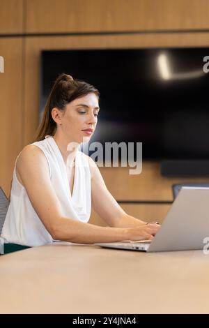 Travailler sur ordinateur portable, femme d'affaires se concentrant sur les tâches dans le cadre de bureau moderne Banque D'Images
